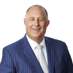 A smiling person in a pinstripe suit and white shirt.