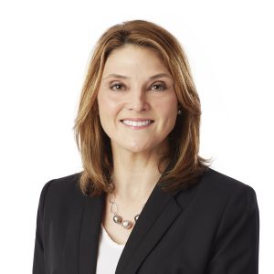 A smiling woman with medium-length hair wearing a black blazer and a necklace with circular elements.