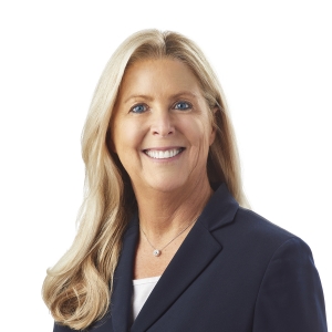 A smiling woman with long blonde hair wearing a dark blazer over a light-colored blouse.