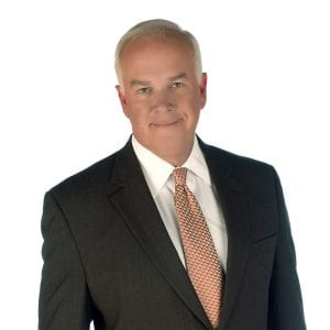 A man in a suit with a tie is posing against a white background.
