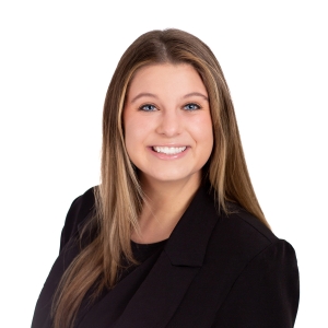 A person with long blonde hair and a big smile is wearing a black blazer.