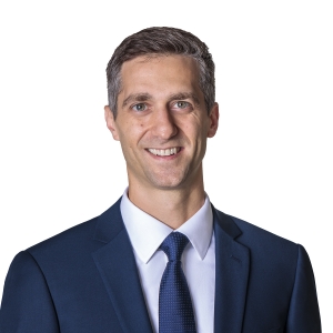 A person in formal business attire smiles against a white background.