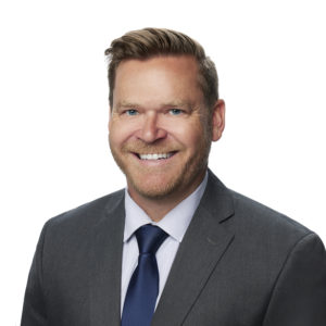 A smiling man is wearing a suit and tie against a white background.
