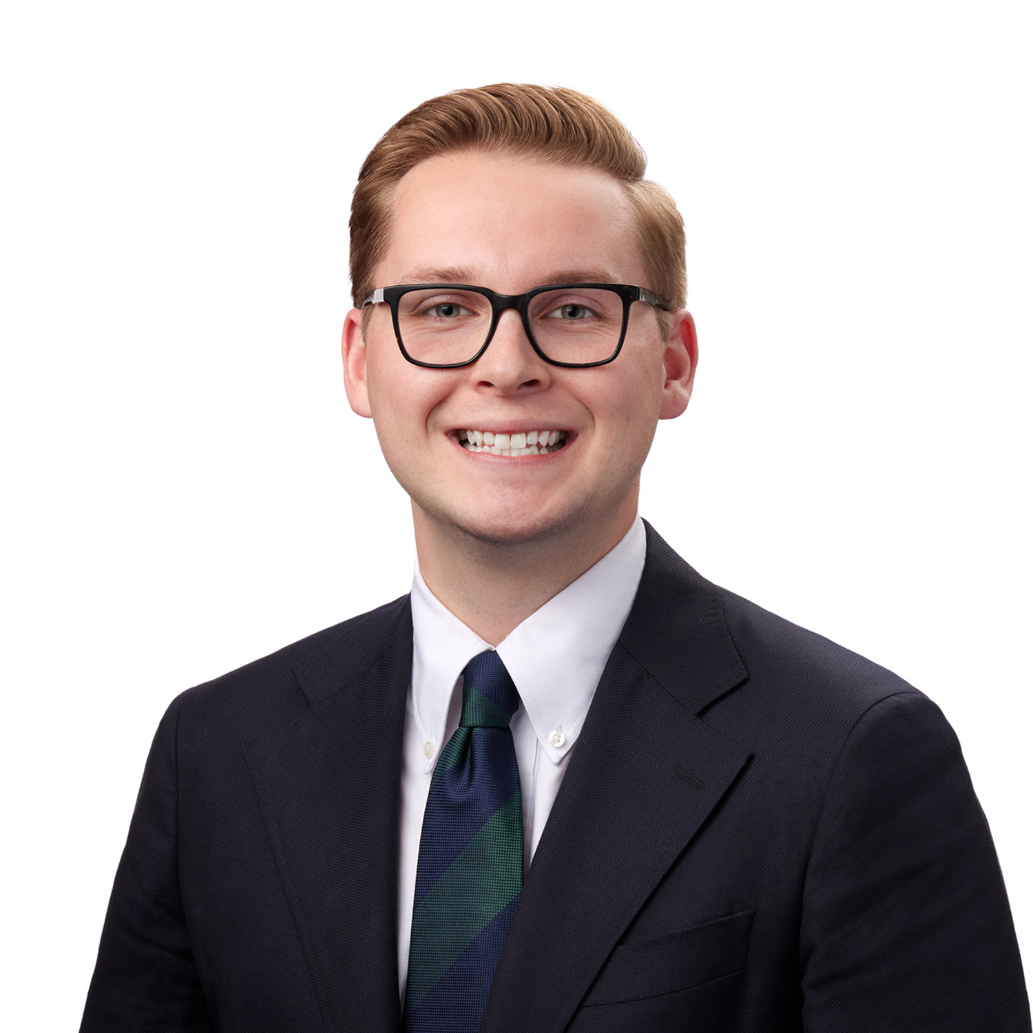 A person with short hair, glasses, and a blue suit is smiling against a plain white background.