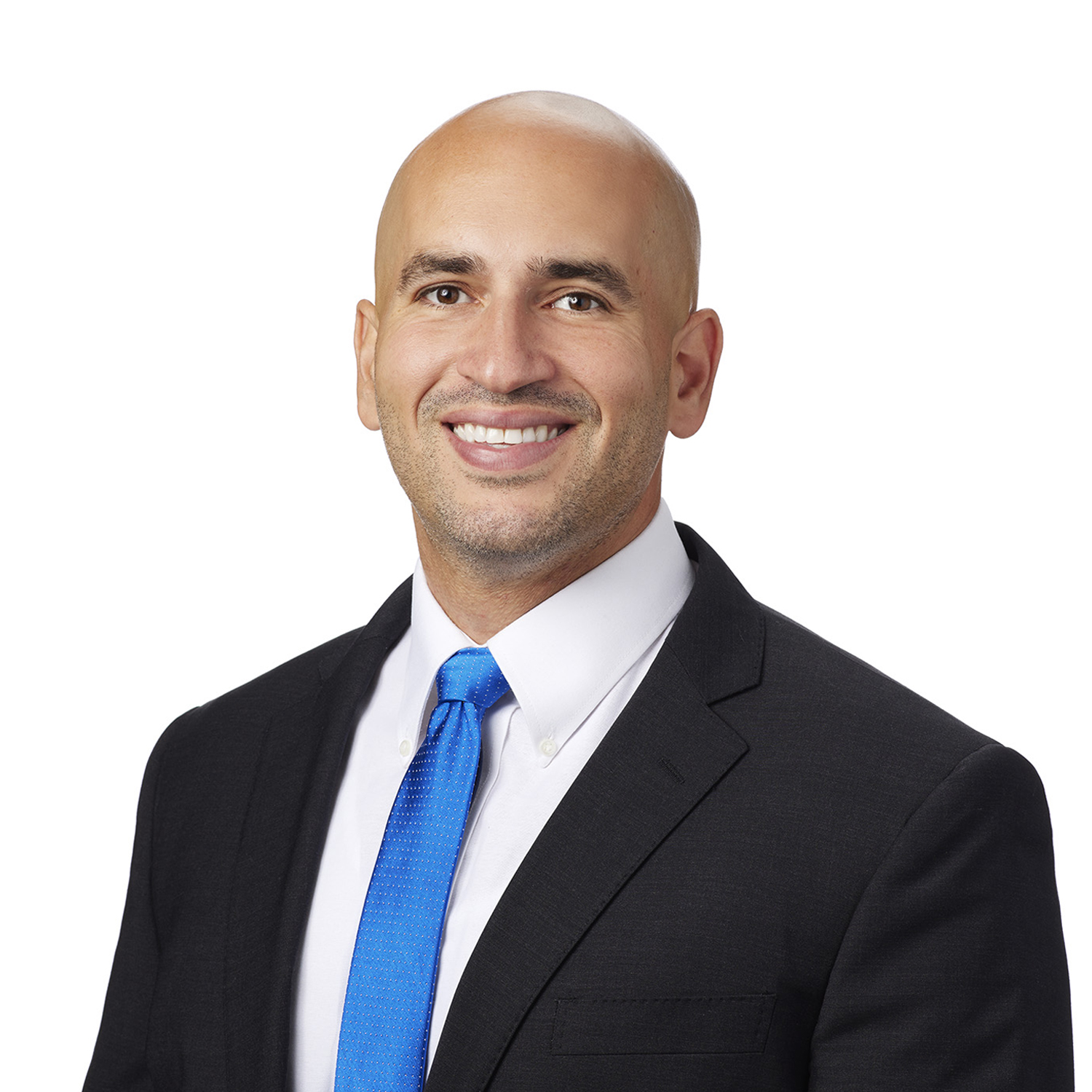 A smiling individual dressed in a black suit with a white shirt and a blue tie.